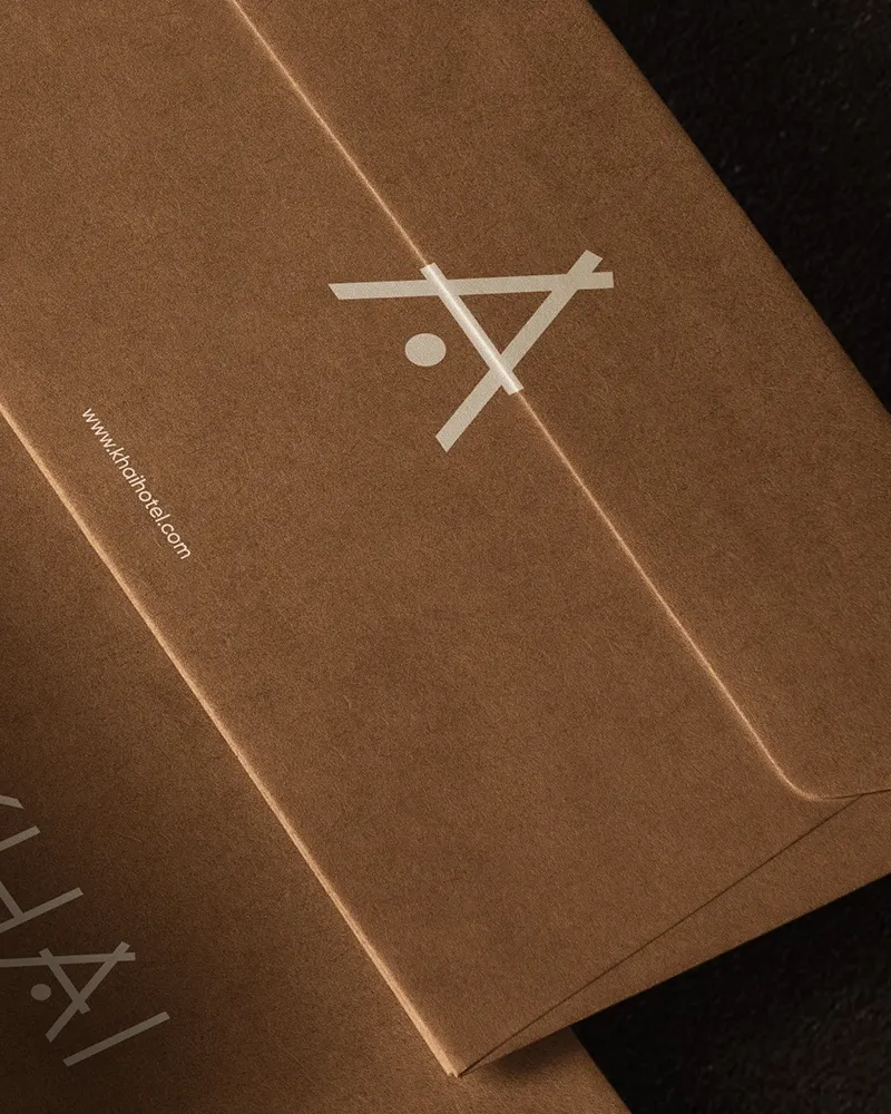Close-up shot of KHAI Hotel branded kraft paper envelope showing rich paper texture and custom monogram emblem